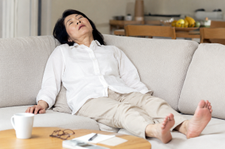 全身疲労でぐったりと疲れてソファに倒れこんでいる女性の姿