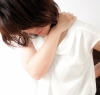 肩痛で肩を押さえている女性の画像