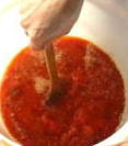 ヘラで醸造中の柿酢をかきまぜる写真