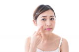 卵白を指先で頬につける女性の写真